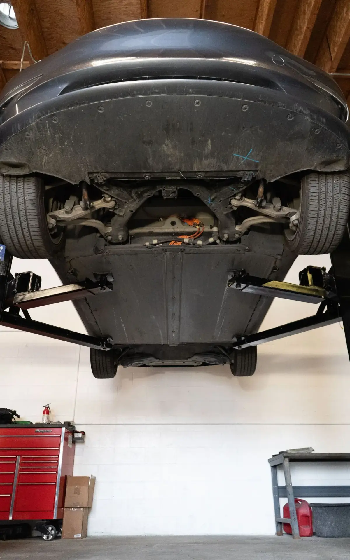 Underside of a Tesla on the lift showing the drive unit