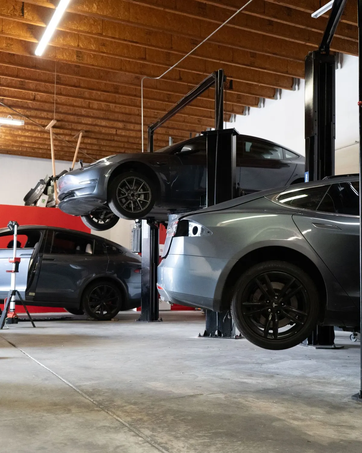 Three Teslas on lifts inside the Electric City shop in Stanton